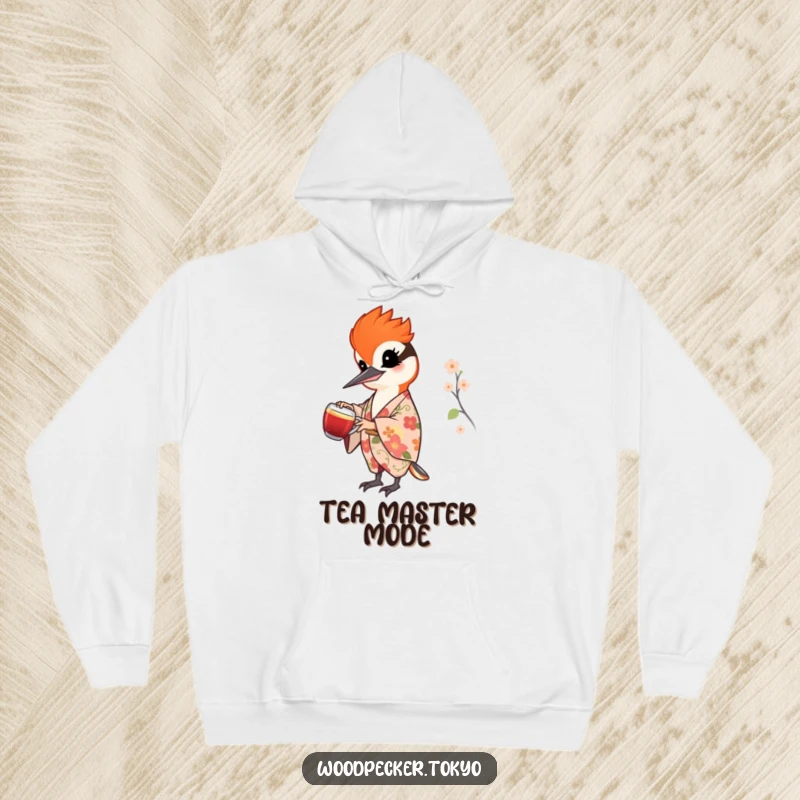Funny hoodie featuring a cheerful woodpecker in a floral kimono pouring tea, offering warmth and a touch of elegant artistry.